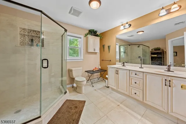 a spacious bathroom with a double vanity sink a toilet a mirror and shower