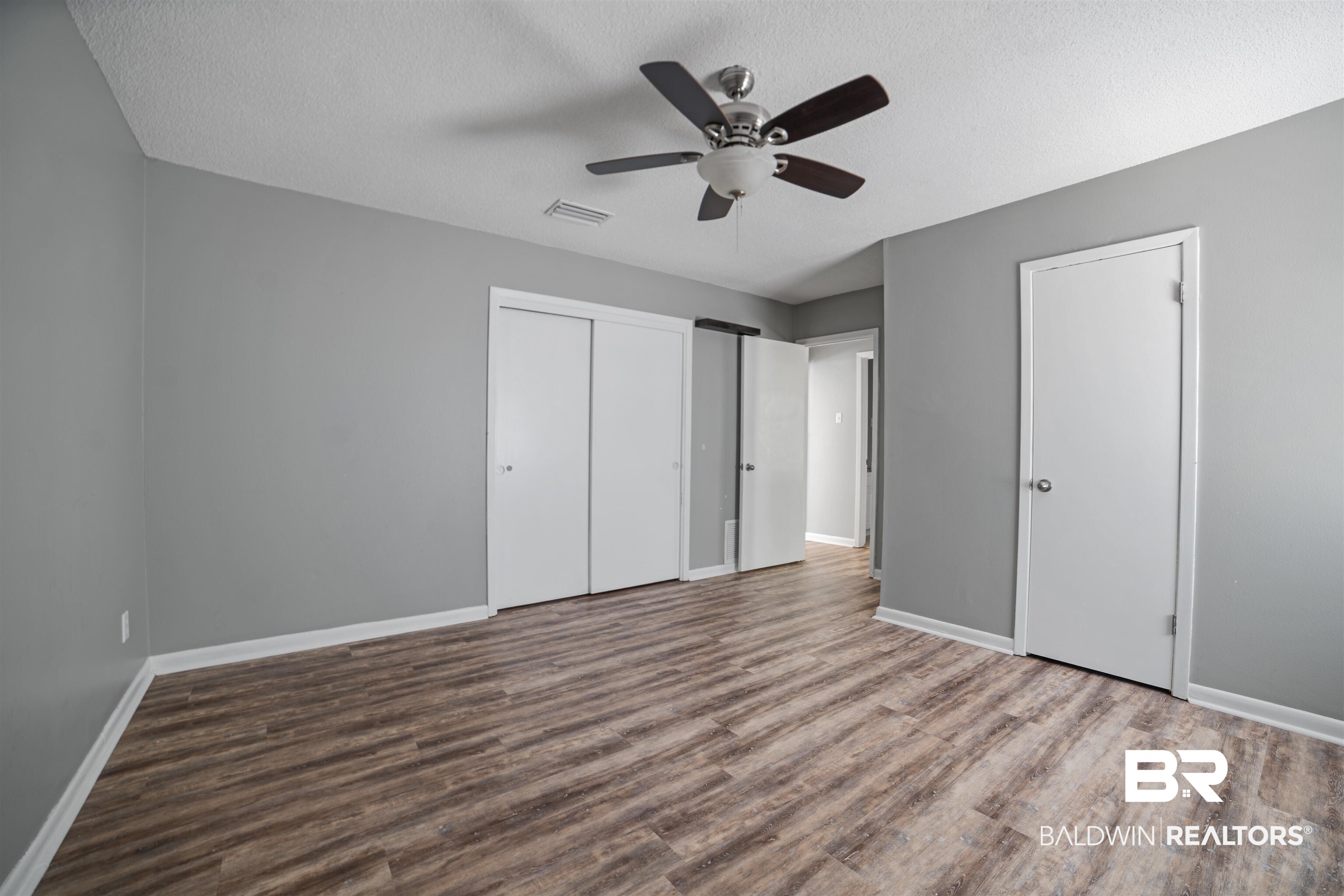 804 Regents Drive West Mobile, AL 36609 - Photo 28 of 35 Unfurnished bedroom featuring a textured ceiling, wood finished floors, two closets, and ceiling fan