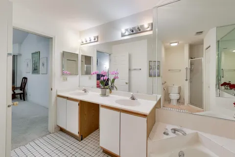 a bathroom with a sink double vanity granite tub shower and a mirror