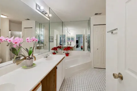 a bathroom with a sink vanity granite tub shower and a mirror