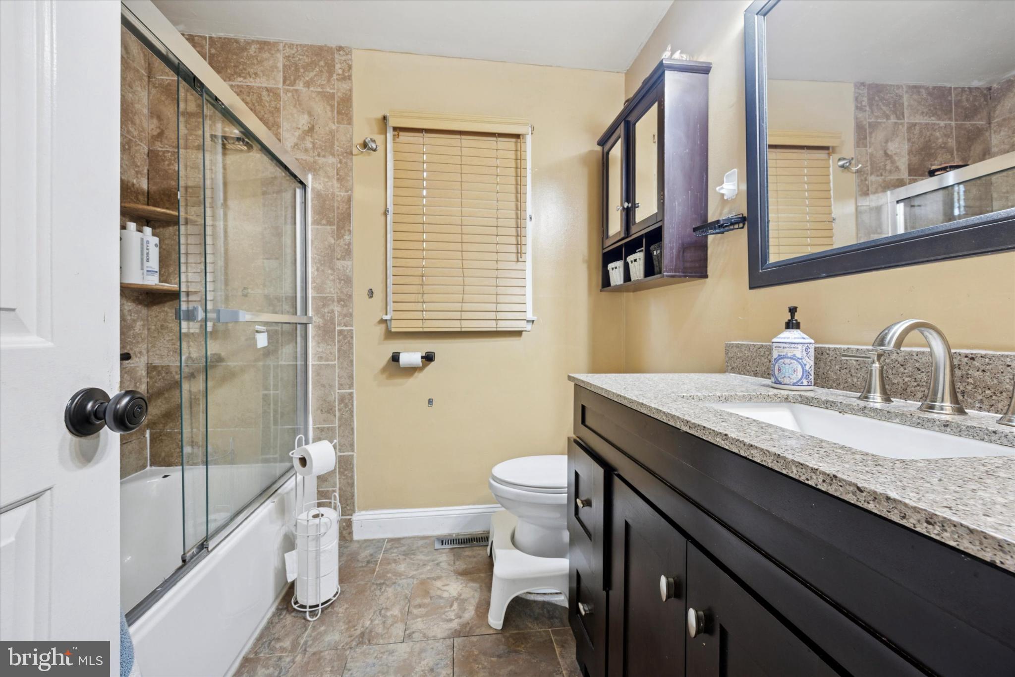 506 Flora Circle Springfield, PA 19064 - Photo 28 of 35 a bathroom with a granite countertop sink a toilet a mirror and shower
