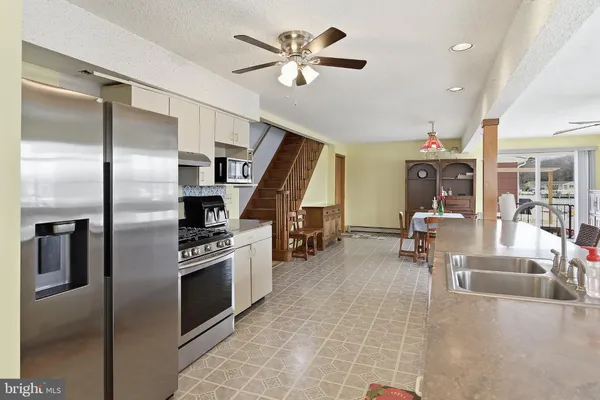 a kitchen with stainless steel appliances kitchen island granite countertop a refrigerator a stove and a sink with cabinets