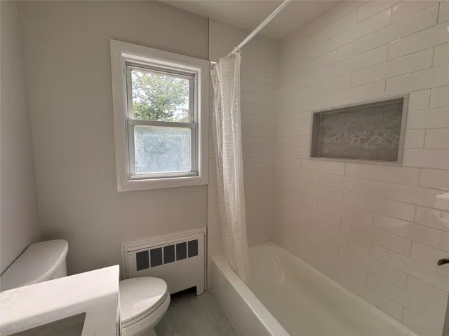 an empty room with wooden floor a fireplace and windows