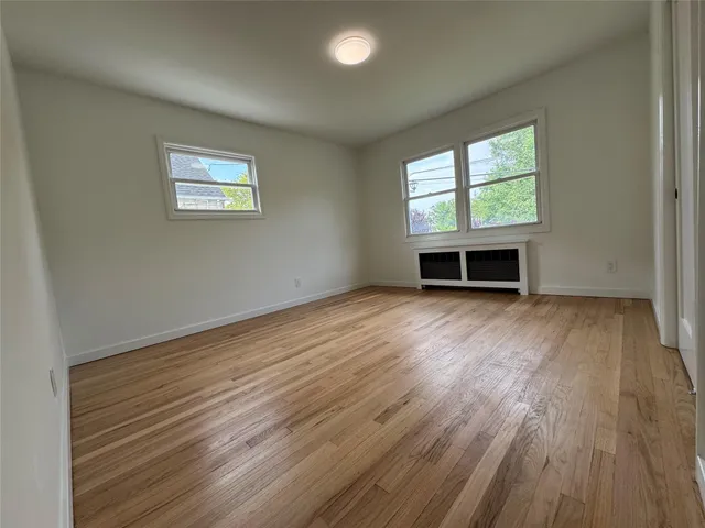 an empty room with wooden floor a fireplace and windows