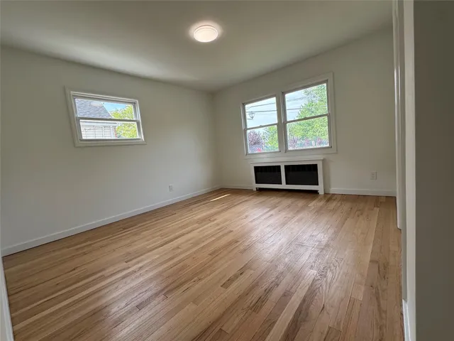 an empty room with wooden floor a fireplace and windows