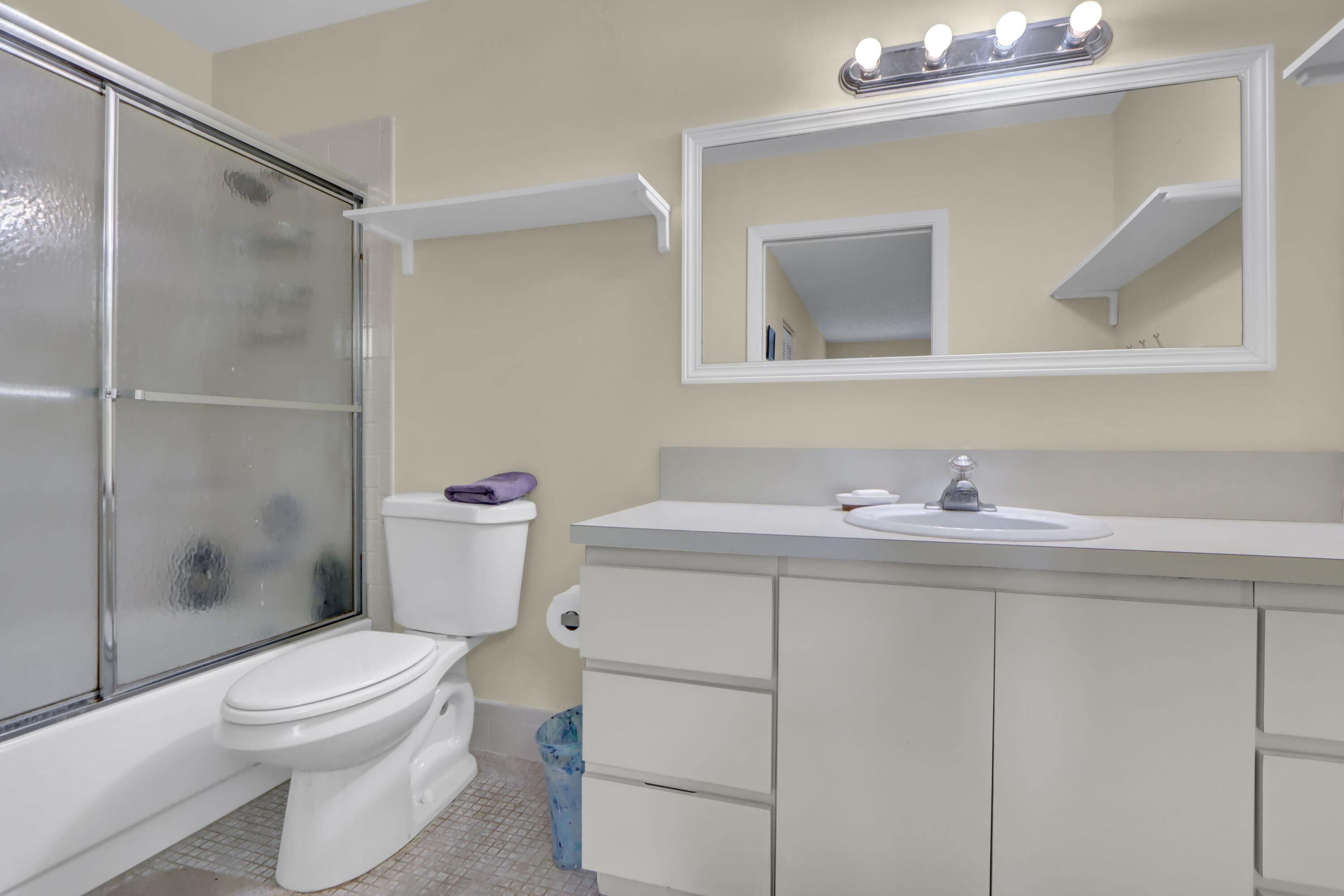 14050 Nesting Way, Unit B Delray Beach, FL 33484 - Photo 14 of 17 a bathroom with a sink a mirror and a toilet