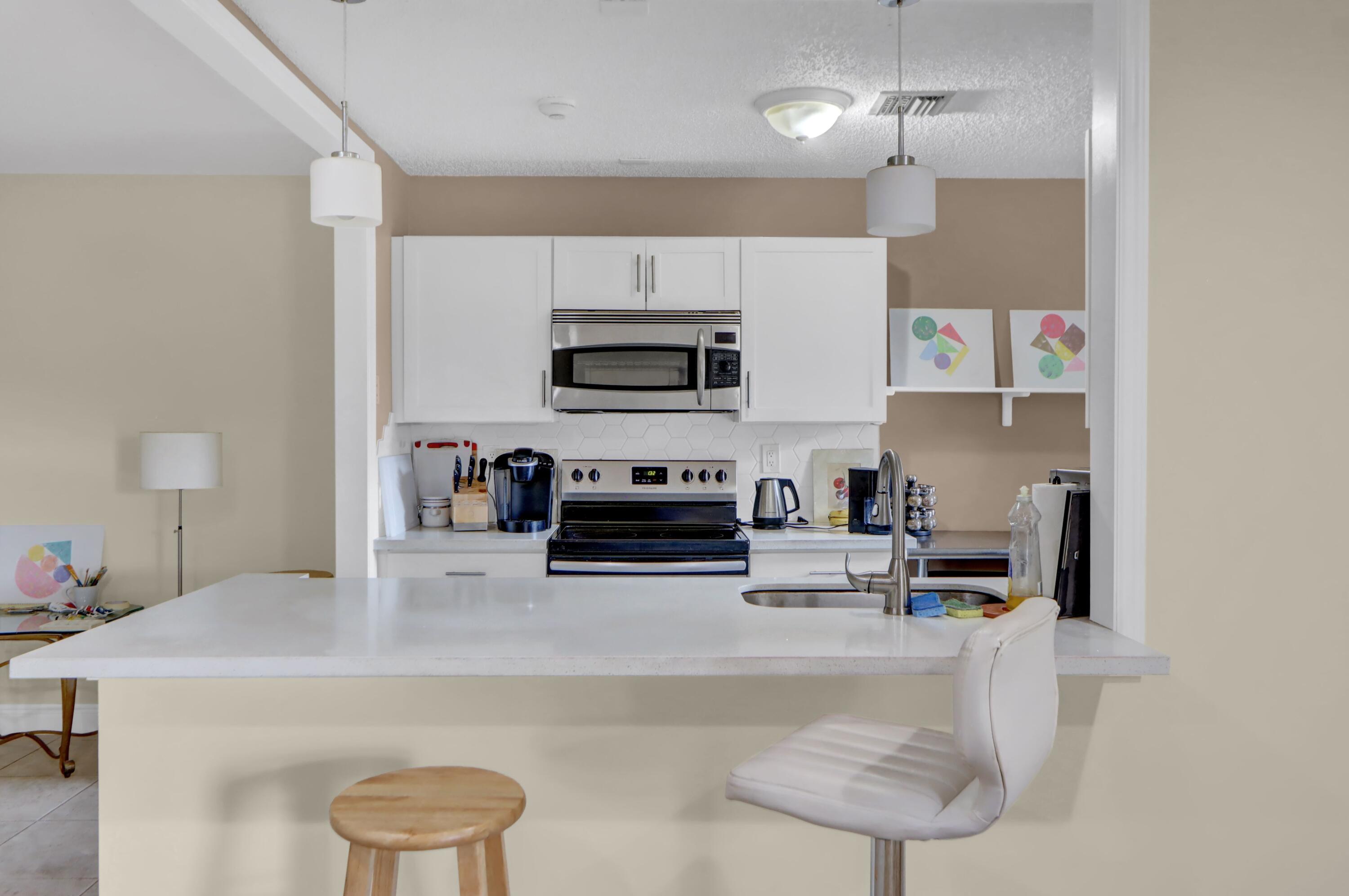 14050 Nesting Way, Unit B Delray Beach, FL 33484 - Photo 8 of 17 a kitchen with a sink a microwave and chairs