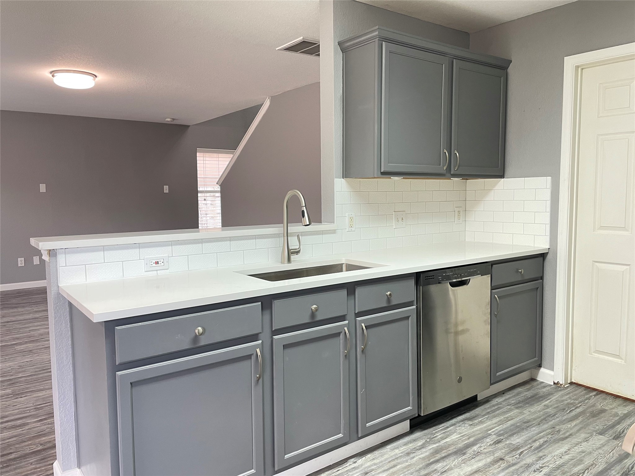 3638 Windhill Loop Round Rock, TX 78681 - Photo 13 of 32 Kitchen featuring gray cabinetry, white countertops, stainless steel dishwasher, undermount sink with a gooseneck faucet, and white subway tile backsplash