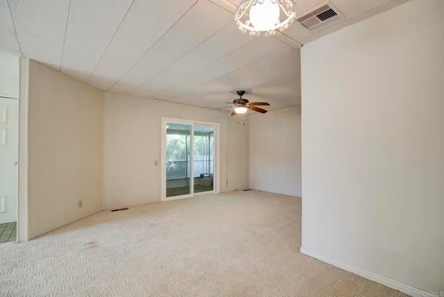 an empty room with a chandelier fan and windows