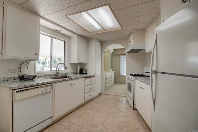a kitchen with granite countertop a sink appliances cabinets and a large window