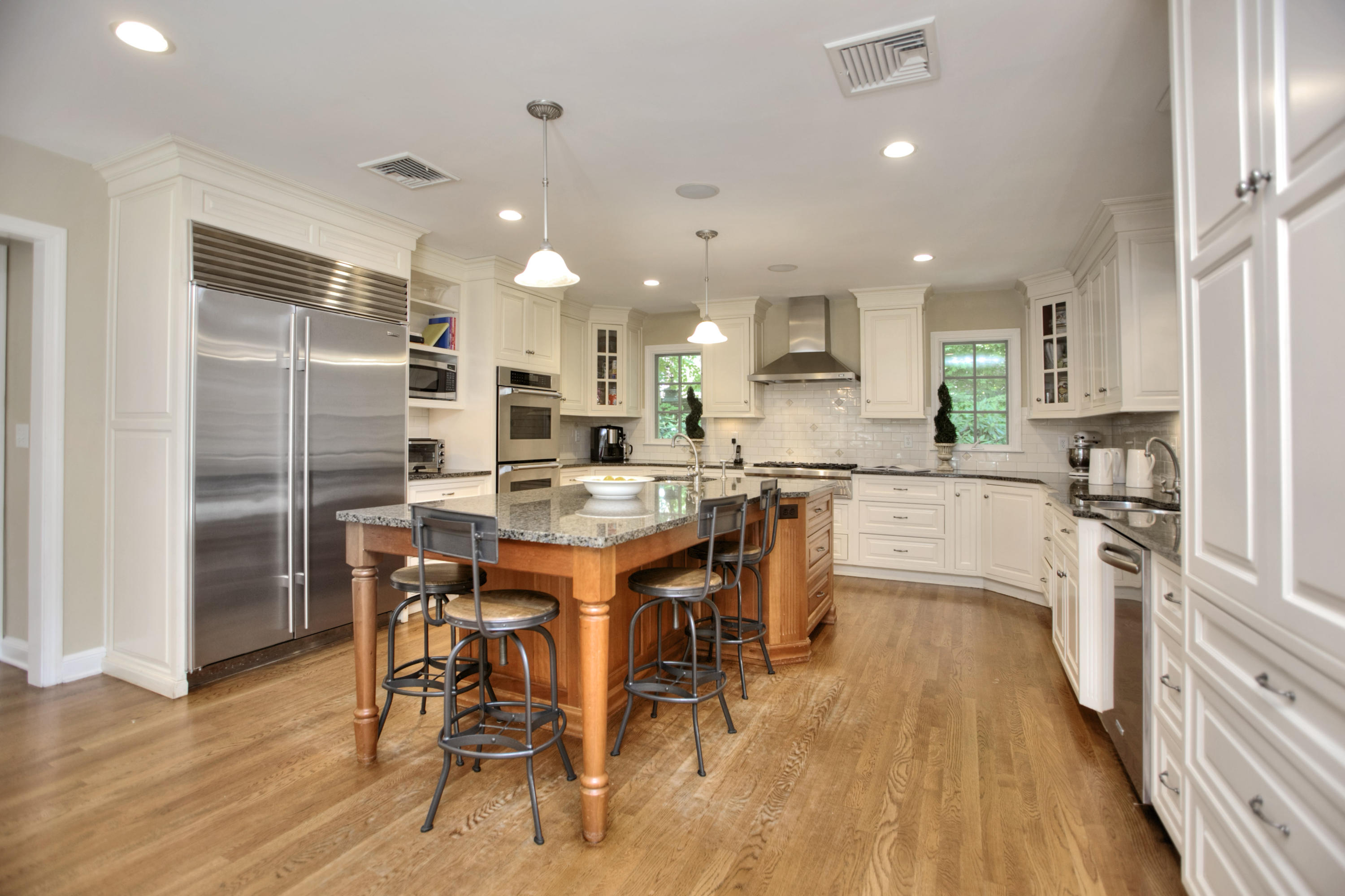 17 Rocaton Road Darien, CT 06820 - Photo 9 of 26 a kitchen with stainless steel appliances kitchen island granite countertop a refrigerator a stove a sink and a dining table with wooden floor