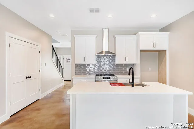a kitchen with stainless steel appliances a stove a sink and white cabinets