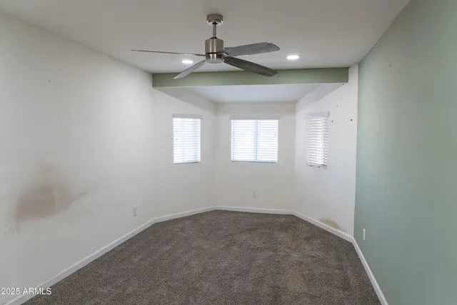 an empty room with a ceiling fan and windows