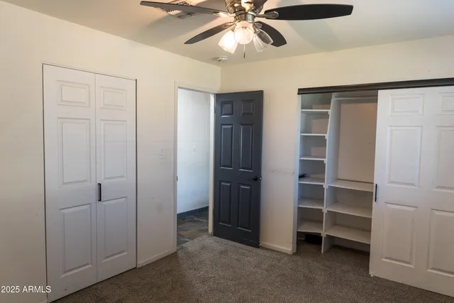 an empty room with closet and a ceiling fan