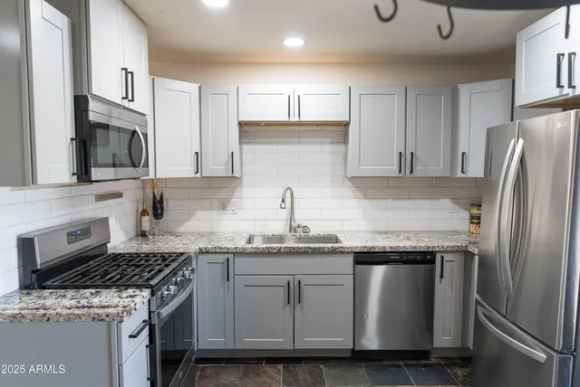a kitchen with granite countertop a sink stove and refrigerator