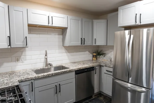 a kitchen with granite countertop a refrigerator and a sink