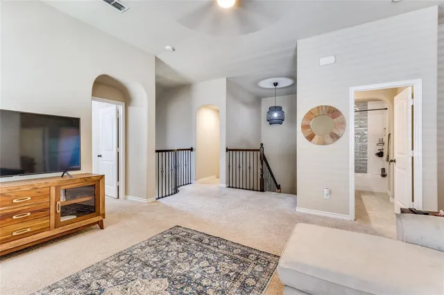 a spacious bedroom with a bed a mirror and lamp on dresser