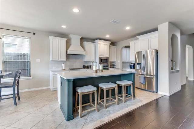 a kitchen with stainless steel appliances granite countertop a refrigerator a stove a sink a dining table and chairs