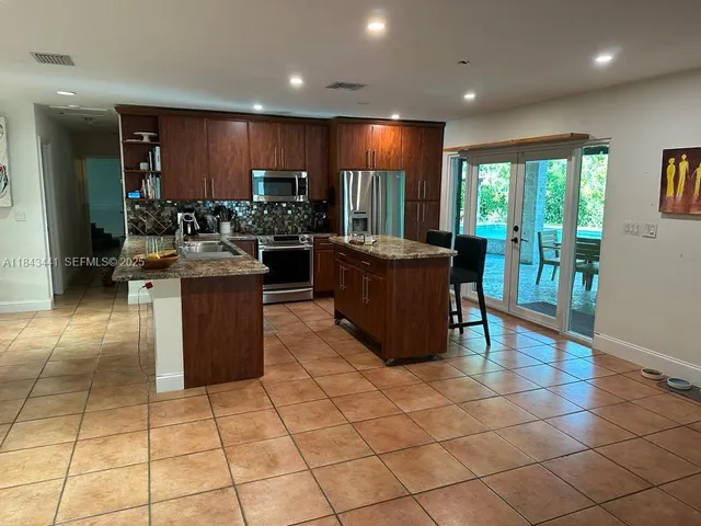 a open kitchen with granite countertop a sink and a stove top oven
