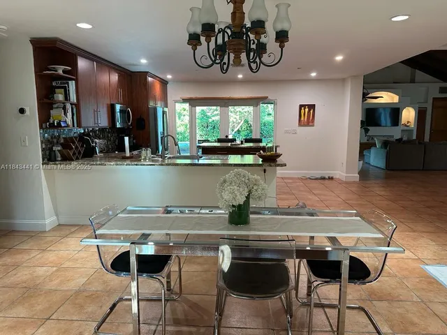a kitchen with kitchen island stainless steel appliances a table chairs in it and wooden floor