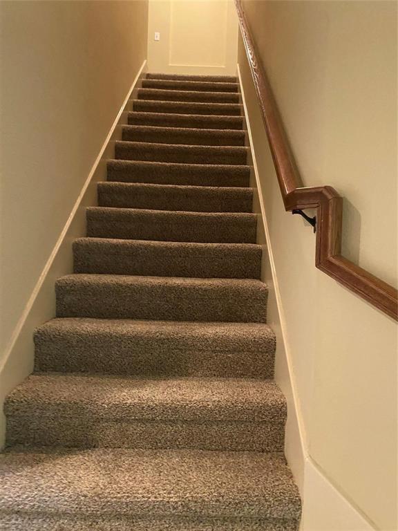 2222 Kirby Street Dallas, TX 75204 - Photo 15 of 25 Carpeted staircase featuring a wood-finish handrail and neutral wall tones