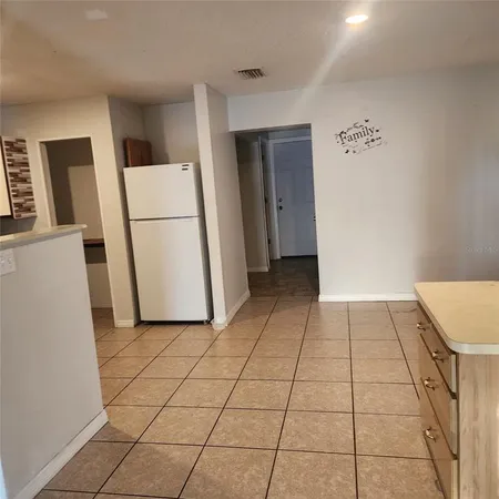 a view of a kitchen with refrigerator and white cabinets