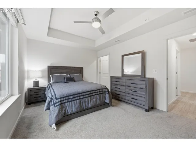 a bedroom with a bed a dresser and potted plants