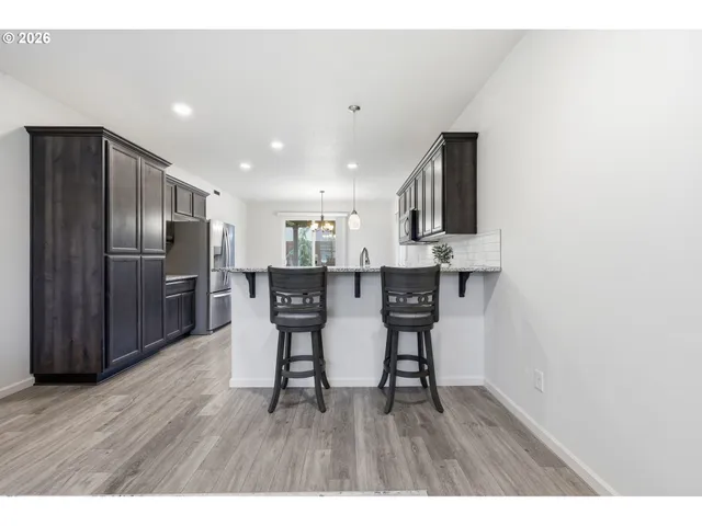 a kitchen with stainless steel appliances a dining table chairs and wooden floor