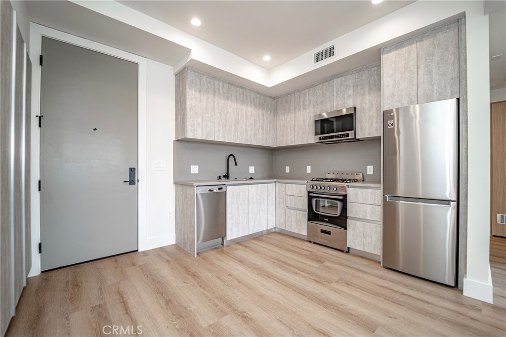 2828 London Street, Unit 304 Los Angeles, CA 90026 - Photo 2 of 23 a kitchen with refrigerator cabinets and wooden floor