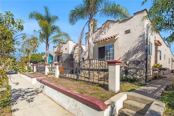 a view of a white house with a small yard and plants