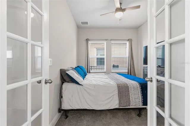 a bedroom with a bed tv on table and a flat screen tv