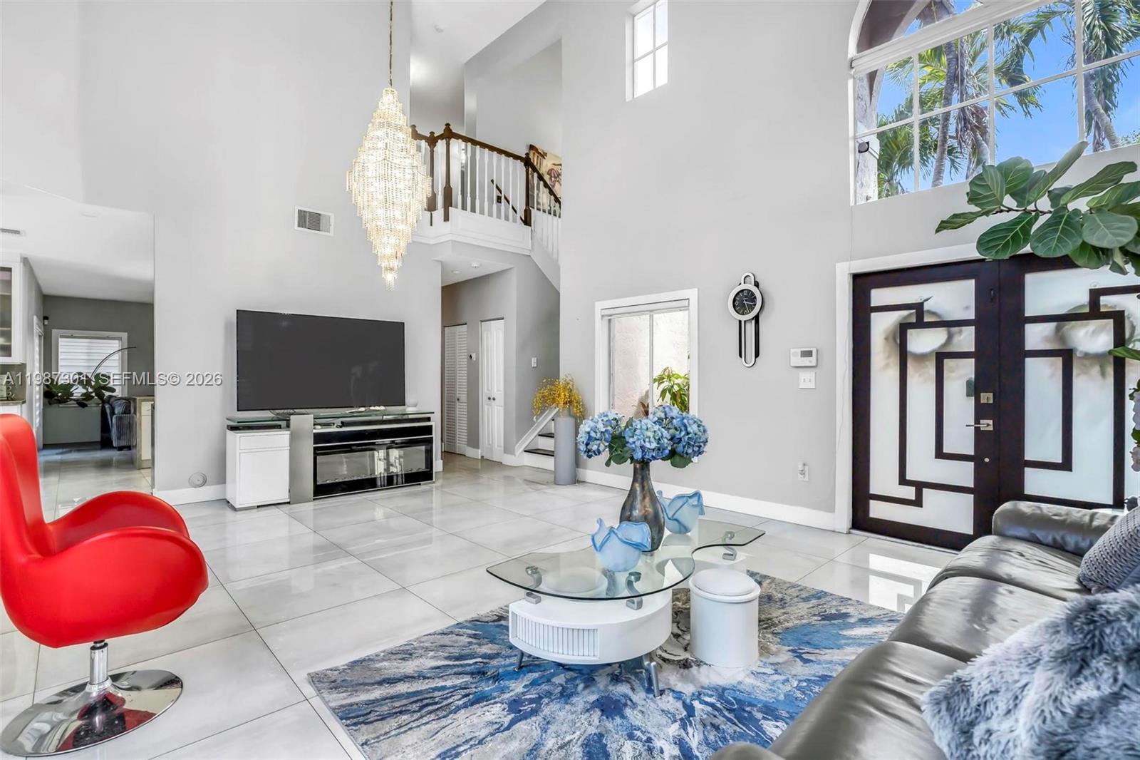 12940 Southwest 142nd Terrace Miami, FL 33186 - Photo 9 of 44 a living room with furniture a chandelier and a flat screen tv
