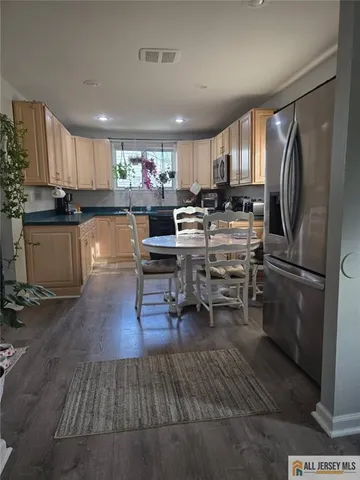 a kitchen with stainless steel appliances a refrigerator a stove a sink dishwasher and a dining table with wooden floor