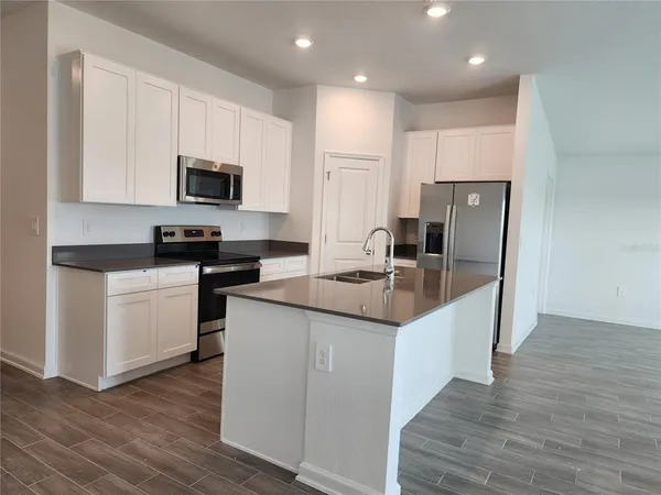 a kitchen with kitchen island granite countertop a sink and steel appliances