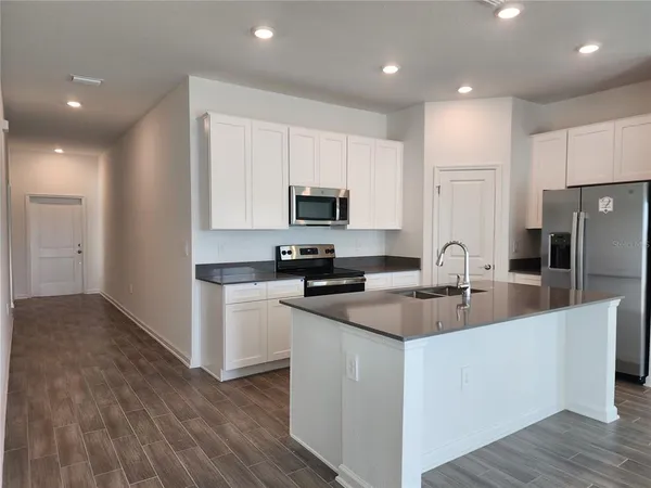 a kitchen with a sink a microwave a refrigerator and cabinets
