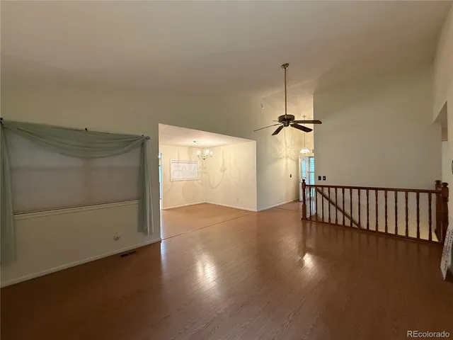 an empty room with wooden floor cabinet and windows