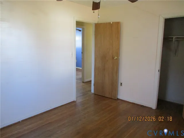 a view of an empty room with closet and wooden floor