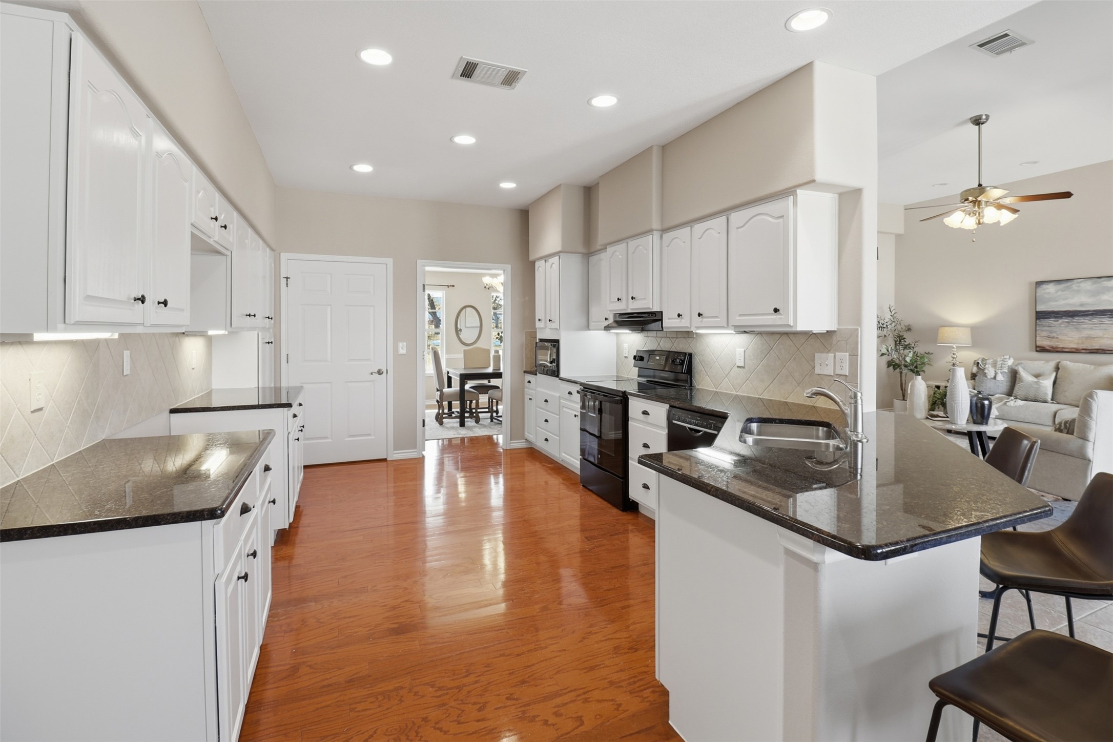 200 Apache Trail Burnet, TX 78611 - Photo 16 of 40 Kitchen with dark stone counters, a breakfast bar, black appliances, white cabinetry, and recessed lighting