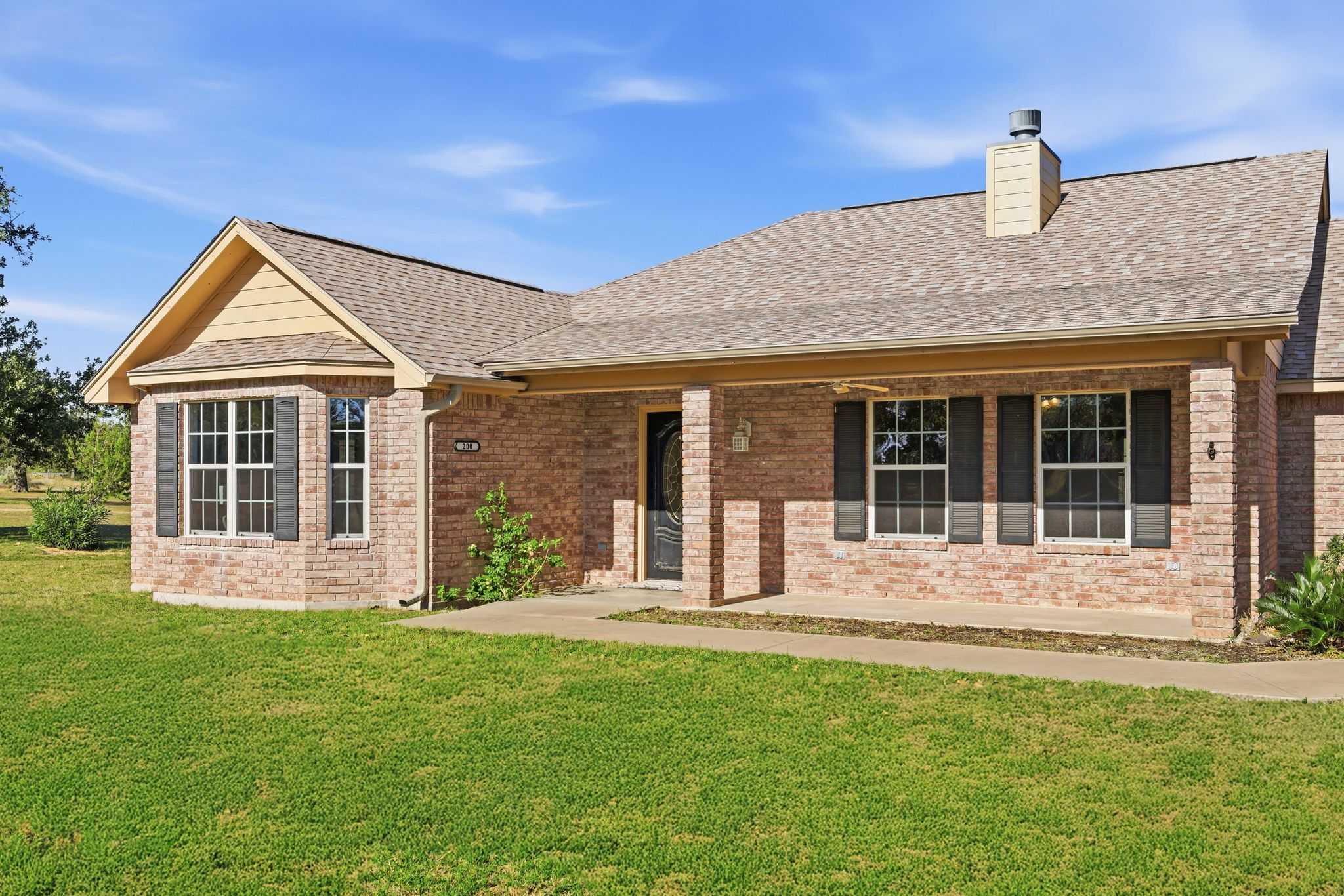 200 Apache Trail Burnet, TX 78611 - Photo 2 of 40 View of front of property with a front lawn, roof with shingles, brick siding, and a porch