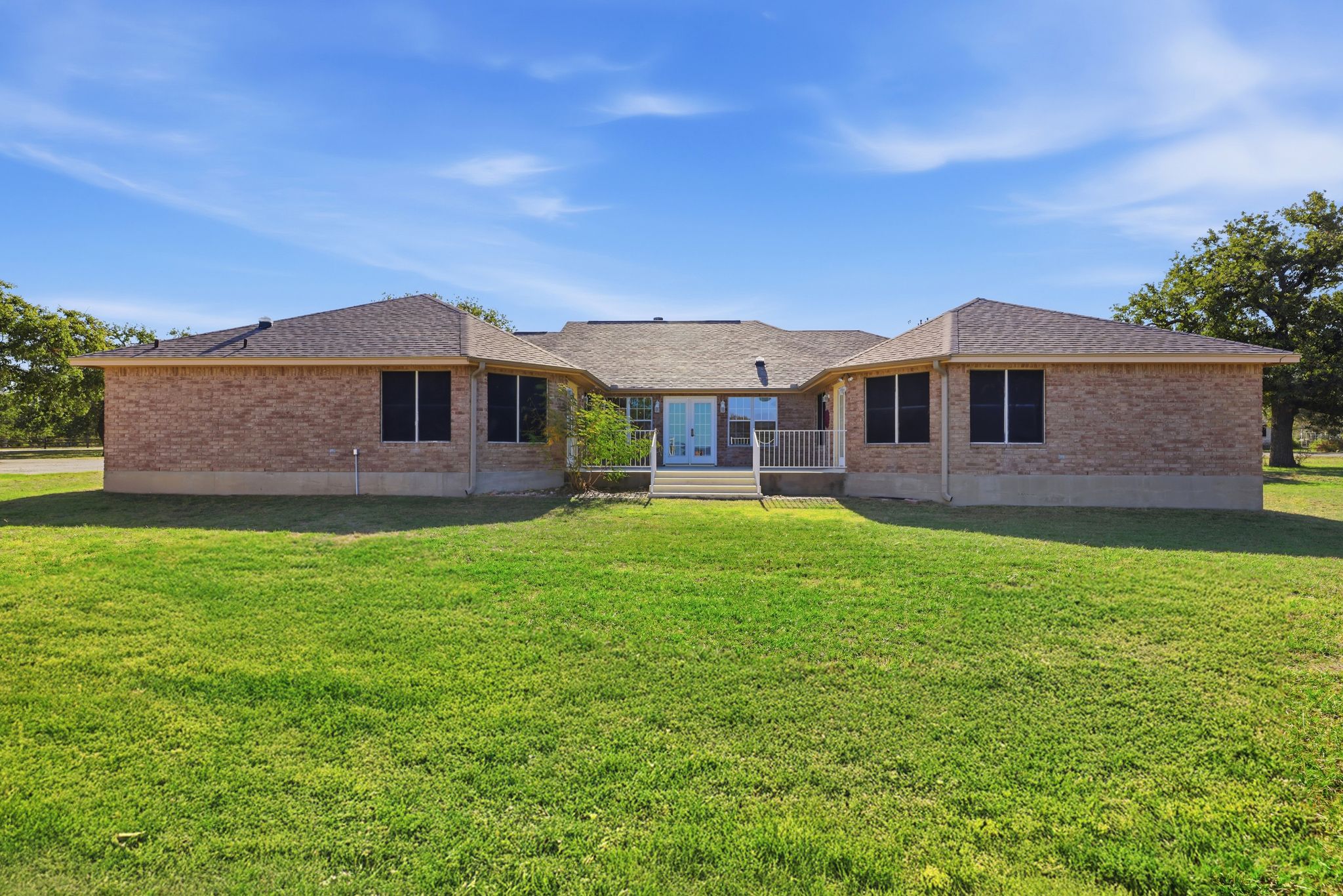 200 Apache Trail Burnet, TX 78611 - Photo 33 of 40 Rear view of house featuring a wooden deck, brick siding, a yard, and roof with shingles