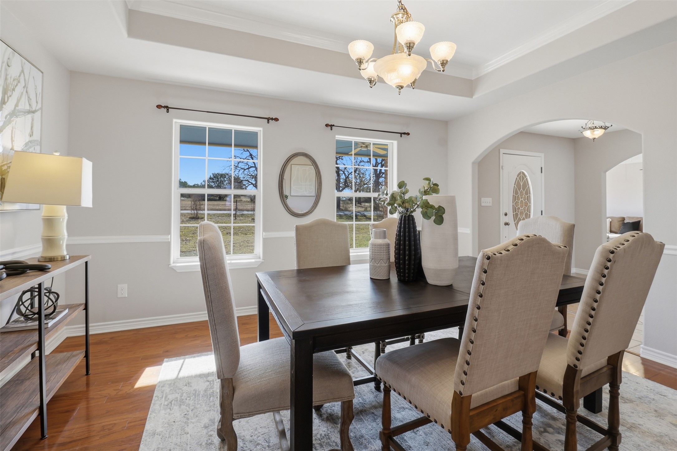 200 Apache Trail Burnet, TX 78611 - Photo 5 of 40 Dining area featuring a chandelier, a tray ceiling, wood finished floors, ornamental molding, and arched walkways
