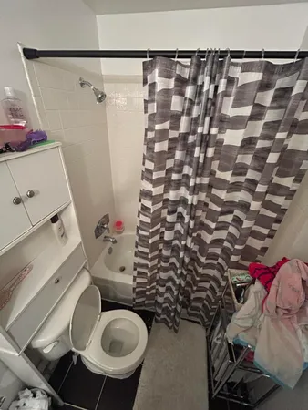 a bathroom with a granite countertop toilet and a shower curtain