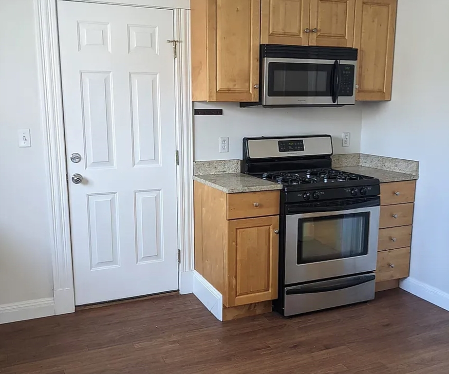 124 Selden Street Boston, MA 02124 - Photo 26 of 35 a kitchen with stainless steel appliances granite countertop white cabinets a stove top oven and microwave