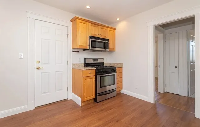 a kitchen with wooden floor and electronic appliances