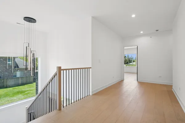 a view of a hallway with wooden floor and a bathroom