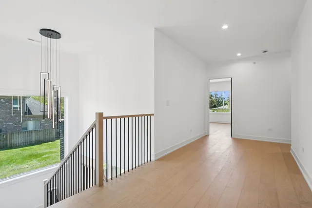 a view of a hallway with wooden floor and a bathroom