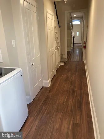 a view of an empty room with wooden floor and a fireplace
