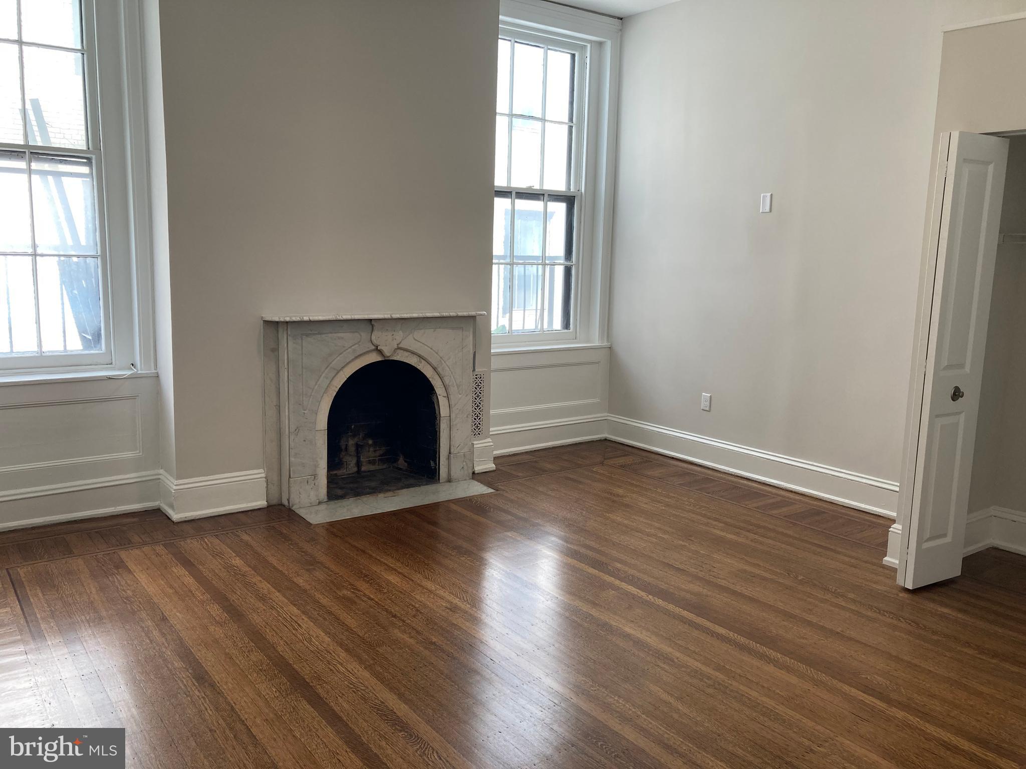 10 East Chase Street Baltimore, MD 21202 - Photo 31 of 60 an empty room with wooden floor and a fireplace