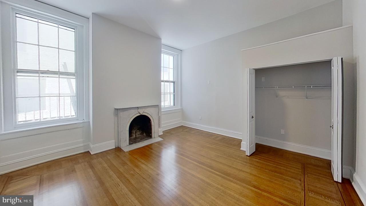 10 East Chase Street Baltimore, MD 21202 - Photo 54 of 60 an empty room with wooden floor fireplace and windows