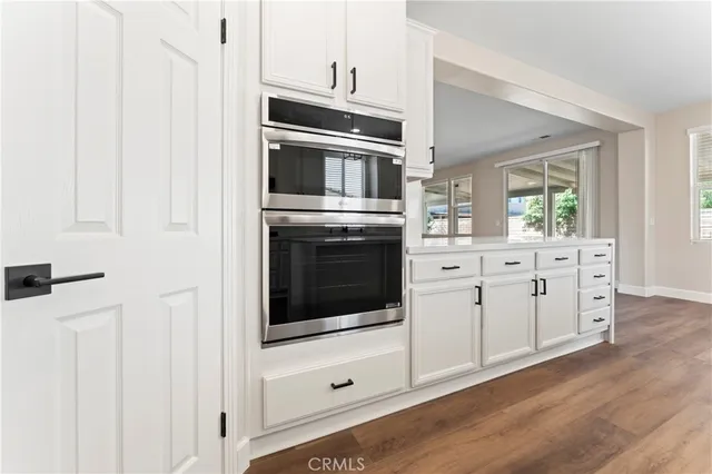 a kitchen with stainless steel appliances white cabinets and wooden floors